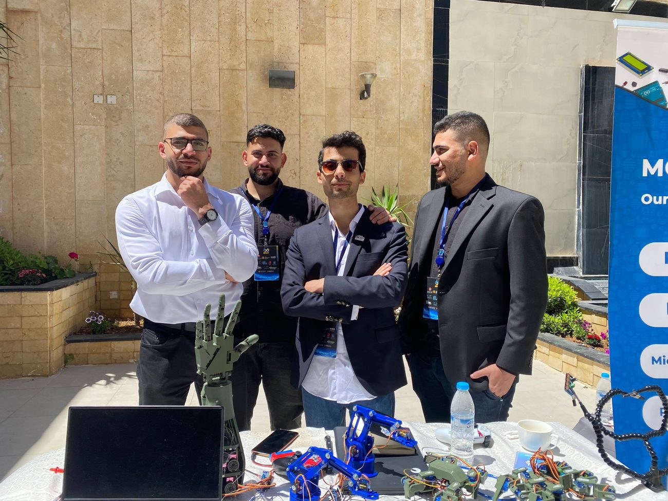 MCC team members with a 3D-printed prosthetic hand and robot arm kits at a conference